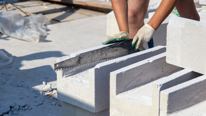 A worker builds the walls of a house from aerated concrete bricks.