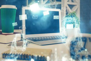 Desktop computer background in office and flying envelops hologram drawing. Double exposure. Electronic mail concept.