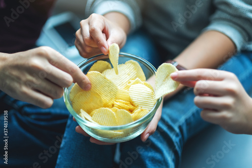 Fotomural Closeup image of friends sharing and eating potato chips at home party