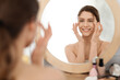 Leinwandbild Motiv Young woman massaging eye zone, looking at mirror
