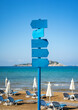 wooden blue signs on a post in a beach under blue sky, with copy space