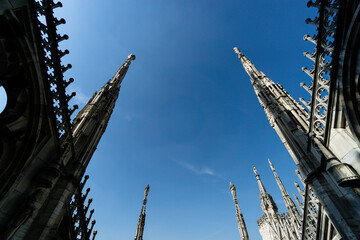 Canvas Print - Low angle shot of spires of Duomo di Milano Italy with blue sky on the background