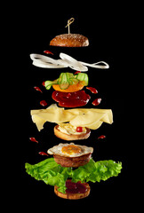 big tasty burger with meat cutlet, cheese, fried egg, tomatoes, cucumber pieces and green lettuce