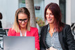 two adult businesswomen working outdoors with laptop