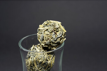 Canvas Print - Closeup shot of tea balls in a glass on a black background