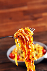 Wall Mural - tagliatelle pasta with tomato sauce parmesan basil on rustic background