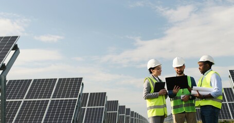portrait of electrician engineers in safety helmet and uniform checking solar panels. group of three