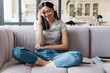 © Drobot Dean - Image of woman listening music with headphones while sitting on sofa