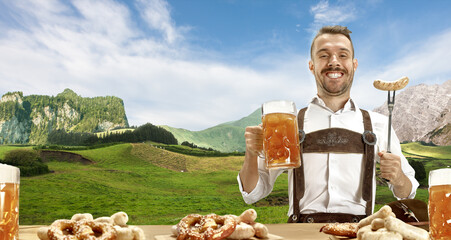 Wall Mural - The happy smiling man with beer dressed in traditional Austrian or Bavarian costume holding mug of beer, mountains on background, flyer ready for ad. The celebration, oktoberfest, festival concept.