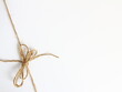 Kokarda z naturalnego sznurka jutowego zawiązana w lewym dolnym narożniku - dekoracja do pakowania wiązania prezentów