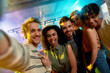 © Svitlana - Join your friends. Close up shot of young men and women smiling while taking selfie. Multiracial group of friends hanging out at party in the bar