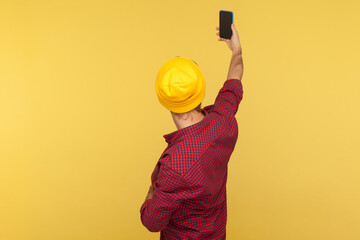 Wall Mural - back view portrait of hipster guy in beanie hat and checkered shirt talking video call, taking selfi