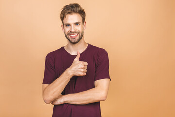 Portrait of a handsome man against beige background with copy space. Guy in casual standing in casual isolated. Successful hispanic man looking at camera. Thumbs up.