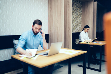 Wall Mural - Man making phone call and notes near woman with notepad