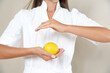 Close up photo of woman's hands in circle with lemon in a white robe.