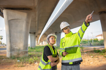 Two engineers discuss about work at the site of large bridge under construction,Management consulting people discussion with engineers about the progress and construction planning of highway