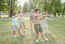 Group Of Focused Senior People And Their Coach Gesturing Hands And Doing Qigong Exercise In Park