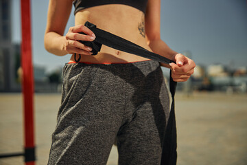 Wall Mural - Cropped shot of attractive young woman with black hand wraps on the sports ground