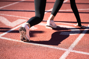 Rear view of woman jogger on running track getting ready to start run. 