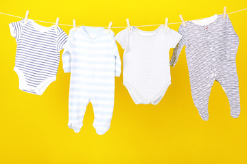 Baby clothes hanging on yellow background