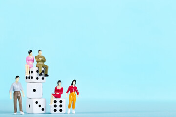 Miniature people with white dices on blue background