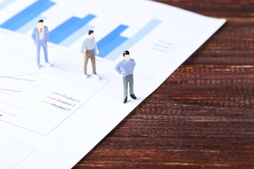 Poster - Miniature people and financial papers with graph and charts on brown wooden table