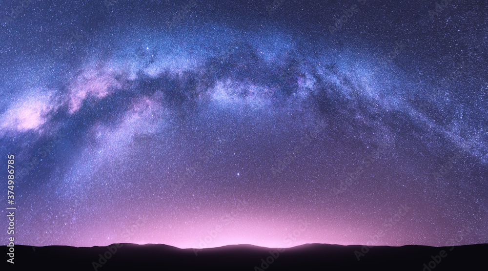 Milky Way arch. Fantastic night landscape with bright arched milky way, purple sky with stars, pink light and hills. Beautiful scene with universe. Space background with starry sky. Galaxy and nature - obrazy, fototapety, plakaty 