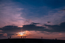 Silhouetted People On Hill As Sunsets