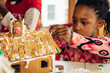 © Gabriel (Gabi) Bucataru/Stocksy - Young black girl working on a gingerbread house