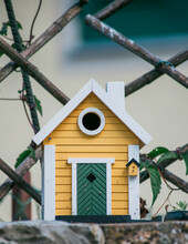 Close Up Of Yellow Birdhouse On Stone Wall