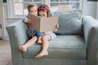 © Jakob Lagerstedt/Stocksy - Young girl and boy toddler sitting on an oversized chair reading a book