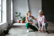 © BONNINSTUDIO/Stocksy - Young trainer assisting mature woman with squats