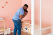 © BONNINSTUDIO/Stocksy - Ethnic father putting baby in cot