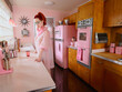 © SuperStock - Vintage styled portrait of woman lost in thought in a mid-century style kitchen.