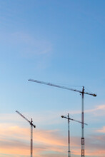 Cranes Of A Construction Site At Sunset