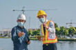 © Suriyo - Two engineer in face mask talking project planing on site construction
