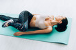 © LIGHTFIELD STUDIOS - High angle view of brunette sportswoman lying on fitness mat while training at home