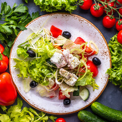 Wall Mural - Greek salad withvegetables,  feta cheese and black olives on a plate. Top view