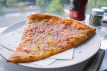 New York Slice Pizza With Condiments On White Table Top With Window Background.