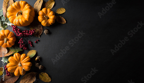 Autumn background decor from dry leaves and pumpkin on blackboard background. Flat lay, top view with copy space for Autumn, fall, Thanksgiving concept.