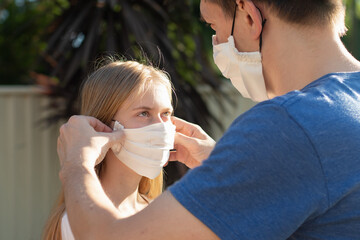 Father helps daughter to put handmade cotton face mask to prevent spreading of the viruses. Coronavirus COVID-19 Concept