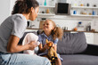 © LIGHTFIELD STUDIOS - african american nanny and babysitter holding toys while looking at each other in kitchen