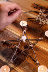 Librate with a crystal pendulum, wooden pentagram and candles, occultism ritual