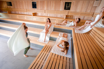 Wall Mural - Traditional sauna ritual performed for group of females in spa center