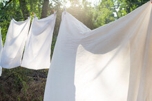 White Bedding, Clothesline Drying, Hanging Outside. Against The Background Of The Rays Of The Setting Sun