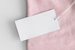 White clothing tag mockup on a soft pink t-shirt.