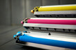 magenta, cyan and yellow toner for color laser printers stacked on gray wooden background