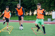 © gorynvd - Two school boys are running ladder drills on the turf during football summer camp. Intense soccer training with coach.