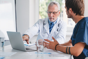 Wall Mural - Senior and young male doctors having meeting at modern medical office