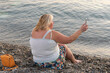 Middle-aged woman using her cell phone at the seashore.